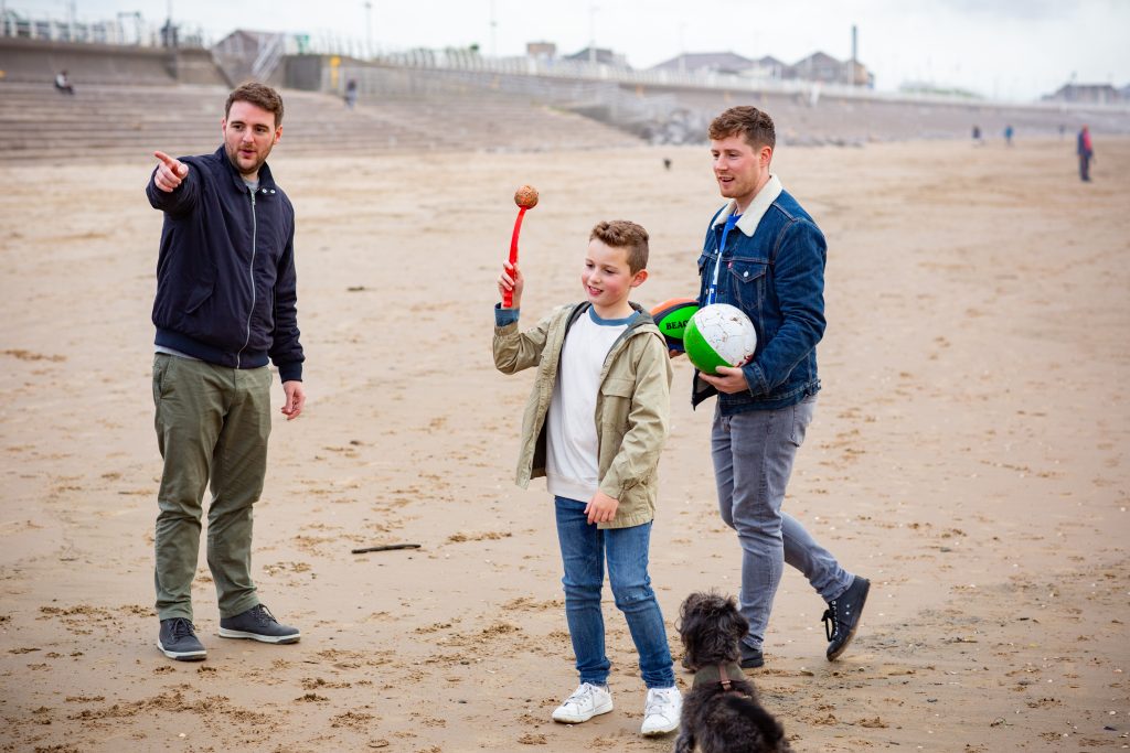 lgbtq+ foster carers with a foster child playing with fetch with a dog